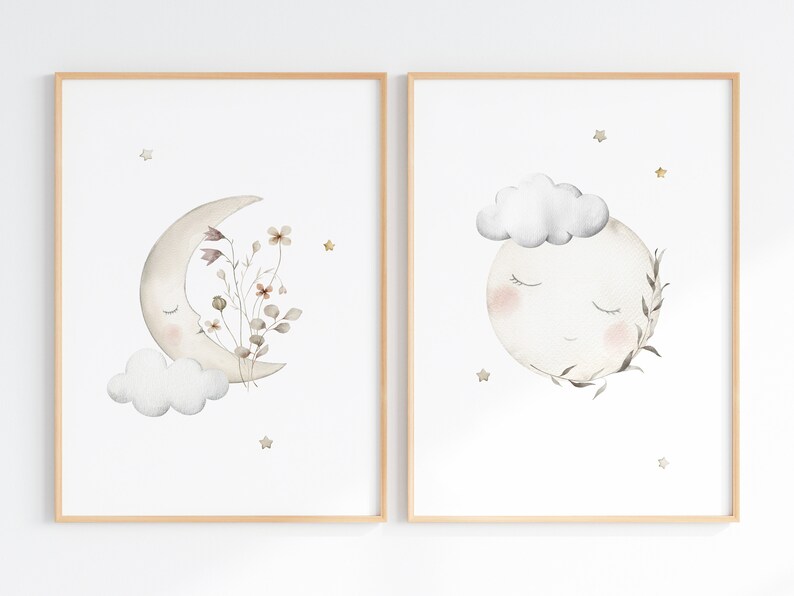 Puede incluir: Dos impresiones enmarcadas con ilustraciones de acuarela de lunas con caras dormidas. Una luna es una media luna con flores y una nube. La otra luna est&aacute; llena con una nube y hojas. Ambas tienen estrellas doradas.