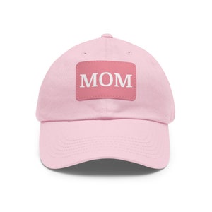 May include: Pink baseball cap with a pink patch that says "MOM" in white letters.