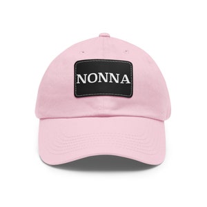 May include: Pink baseball cap with a black patch that says "NONNA" in white letters.