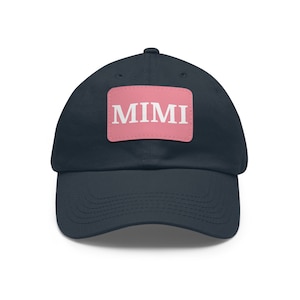 May include: A navy blue baseball cap featuring a pink patch with the white word "MIMI". The cap has a curved peak and an adjustable strap. This hat is a stylish accessory for everyday wear.