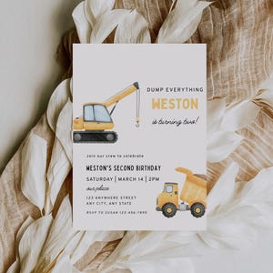 May include: A rectangular birthday invitation card featuring a yellow crane and a yellow dump truck illustration. The text reads: DUMP EVERYTHING WESTON is turning two! Join our crew to celebrate WESTON'S SECOND BIRTHDAY SATURDAY MARCH 14 2PM our place.