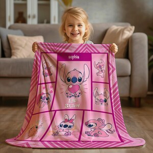 May include: Pink blanket featuring the character Stitch from Lilo & Stitch, with the name "Sophia" printed at the top. The blanket has a grid design with various Stitch illustrations and a heart. The blanket is held up by a person.