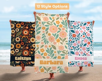 May include: Three beach towels with floral patterns are displayed on a beach. The towels are held up by people. The towels have different floral designs in various colors, including orange, pink, and blue. The text "12 Style Options" is at the top.