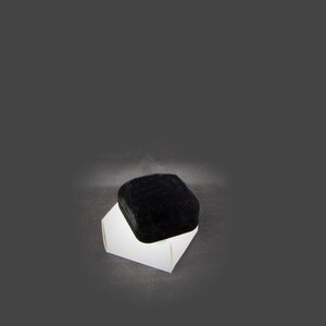 May include: A black velvet ring box with a white cardboard base.