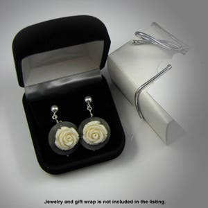 May include: A pair of white rose earrings in a black velvet jewelry box. The earrings are made of carved bone and have a silver tone finish.