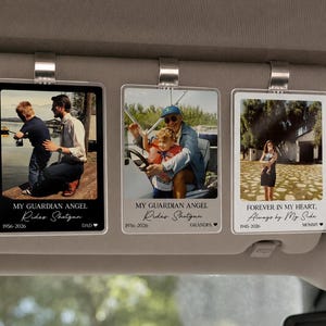 May include: Three rectangular acrylic car visor clips featuring personalized photo prints. The left and center clips display the text MY GUARDIAN ANGEL Rides Shotgun with dates and names. The right clip displays FOREVER IN MY HEART, Always by My Side.