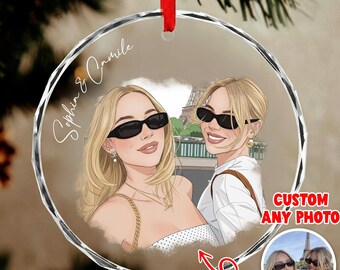 May include: A clear, round ornament with a custom photo of two women wearing sunglasses in front of the Eiffel Tower. The ornament has a red ribbon for hanging and the text "2D FLAT" and "CUSTOM ANY PHOTO". The names "Sophia & Camille" are written on the ornament.