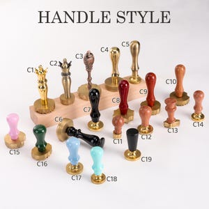 Op de afbeelding: Een verzameling lakzegelstempels met verschillende handvatstijlen. De handvatten zijn in goud, brons, zwart, rood en houttinten. De tekst "HANDLE STYLE" staat bovenaan de afbeelding. De stempels zijn gerangschikt op een houten blok en een wit oppervlak.