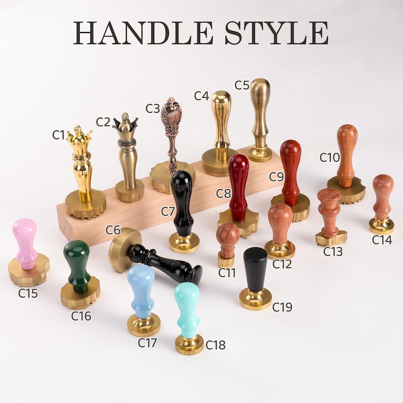 Op de afbeelding: Een verzameling lakzegelstempels met verschillende handvatstijlen. De handvatten zijn in goud, brons, zwart, rood en houttinten. De tekst "HANDLE STYLE" staat bovenaan de afbeelding. De stempels zijn gerangschikt op een houten blok en een wit oppervlak.