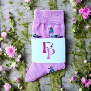 May include: A pair of pink socks featuring a pigeon design. The socks have a white tag with the letters "FP" in pink.