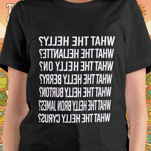 Puede incluir: Camiseta negra con texto blanco dispuesto verticalmente. El texto incluye frases como "MHVL THE HETTA CABK2S" y "SYJ3H 3HT TAHW". Una prenda casual adecuada para el uso diario.