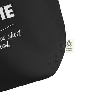 May include: Black tote bag with white text that reads "Life is too short for bad food." The bag has a green certified organic label.