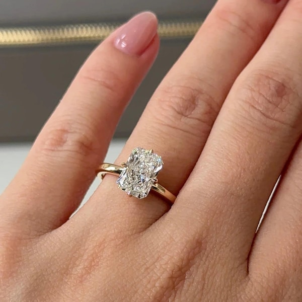 Pierścionek zaręczynowy z 2-karatowym moissanitem o wydłużonym szlifie poduszkowym, pierścionek z diamentem o szlifie poduszkowym z pazurami i kompasem oraz pierścionek z soliterem o szlifie poduszkowym ze złota 14-karatowego.