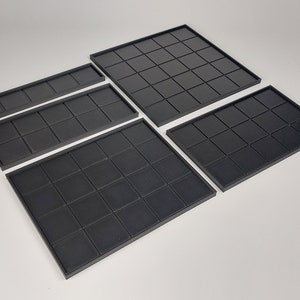 Peut inclure: Quatre tapis de jeu carr&eacute;s en noir de diff&eacute;rentes tailles. Les tapis sont faits d'un mat&eacute;riau flexible et ont un motif en grille.