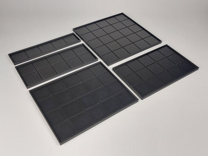 Peut inclure: Quatre tapis de jeu carr&eacute;s en noir de diff&eacute;rentes tailles. Les tapis sont faits d'un mat&eacute;riau flexible et ont un motif en grille.