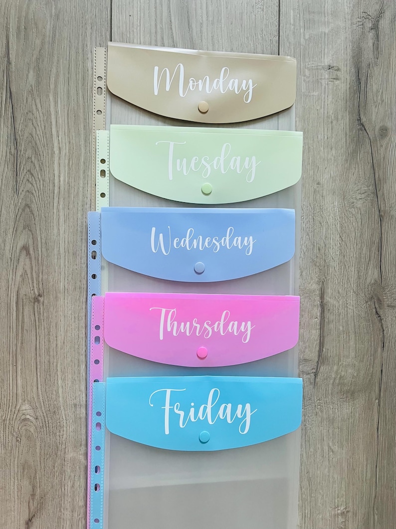 May include: Five clear plastic folders with different coloured fronts and white text. The folders are labelled Monday, Tuesday, Wednesday, Thursday, and Friday.