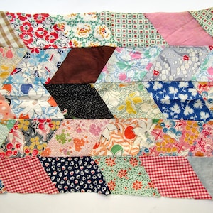 May include: A rectangular patchwork quilt top composed of numerous fabric scraps sewn together in a diamond pattern. The textile features a variety of colorful prints including floral, gingham, polka dot, and geometric motifs in red, blue, and yellow.
