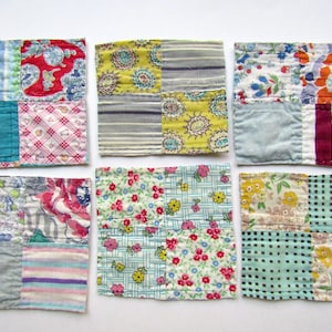 May include: A set of five square fabric coasters, each featuring a four-patch quilt design. The coasters are constructed from various cotton scraps in assorted colors, including red, blue, yellow, green, and pink, with floral, striped, and checkered patterns.