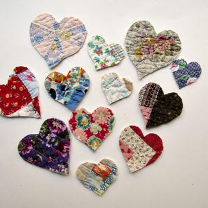 May include: A collection of twelve heart-shaped fabric ornaments featuring various quilted patterns, including floral, plaid, and geometric prints in colors such as red, blue, purple, green, brown, and white, arranged in a scattered formation.