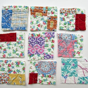 May include: A set of eight square fabric coasters made from quilted patchwork scraps. Each coaster features a unique combination of colorful floral, plaid, and geometric cotton prints in shades of red, blue, yellow, pink, and green.
