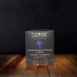 Op de afbeelding: Een zwarte doos met de tekst "CULTURE shrooms" en "MUSHROOM HOT CHOCOLATE & COCOA" met een paarse paddenstoel afbeelding. De doos vermeldt ook "FUNCTIONAL MUSHROOMS" en "CULTURESHROOMS.COM".