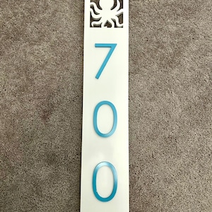 Puede incluir: Un letrero rectangular blanco con un recorte de pulpo azul en la parte superior y el n&uacute;mero 700 en n&uacute;meros azules.