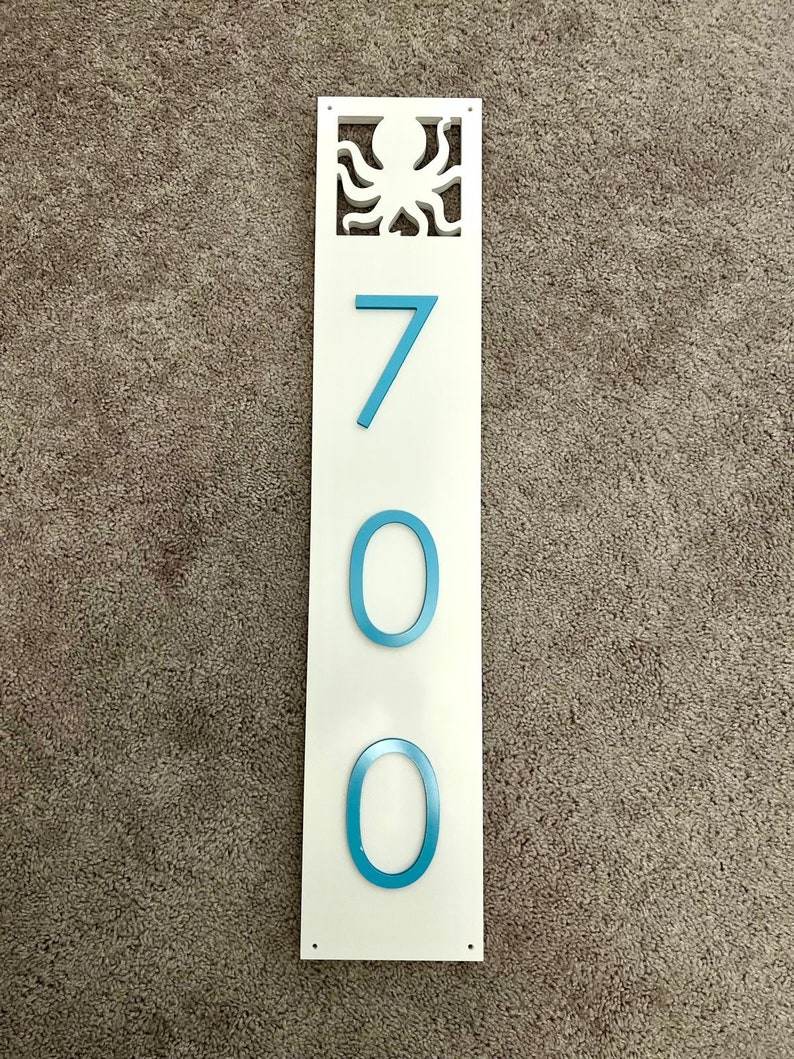 Puede incluir: Un letrero rectangular blanco con un recorte de pulpo azul en la parte superior y el n&uacute;mero 700 en n&uacute;meros azules.