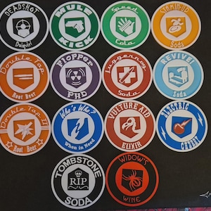 Pode incluir: Uma coleção de dezasseis bases para copos circulares com vários desenhos e texto. Cada base para copos apresenta um gráfico e texto diferente, incluindo "DEADSHOT", "MULE KICK" e "DOUBLE TAP". As bases para copos são em várias cores, incluindo preto, verde, laranja e azul.