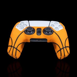 Könnte beinhalten: Orangefarbener und schwarzer PlayStation 5-Controller mit Basketballmuster.