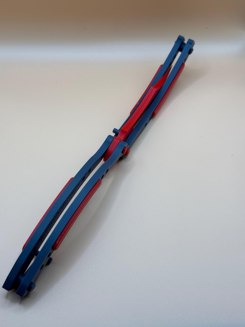 May include: A blue and red butterfly knife with a folding blade. The knife is closed and has a red handle.