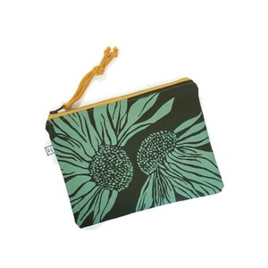 May include: A green zippered pouch with a floral print of two large sunflowers. The pouch has a mustard yellow zipper pull.