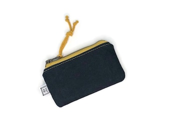 May include: A small black zippered pouch with a yellow zipper and a yellow drawstring. The pouch has a white label with the text "R-E" on it.