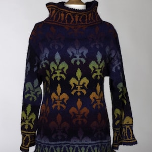 May include: A colorful knitted sweater with a high neck and a pattern of fleur-de-lis. The sweater is a gradient of colors, starting with brown at the neck and fading to green at the hem.