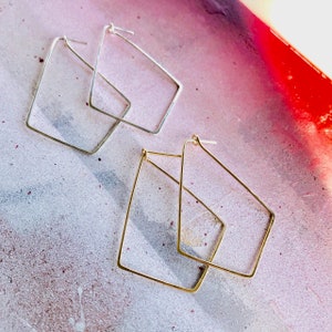 May include: Two pairs of geometric hoop earrings. One pair is silver and the other is gold.