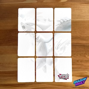 May include: Nine white playing cards with detailed, embossed designs. The cards are arranged in a three-by-three grid on a wooden surface. The bottom right card features the "WHITE FLARE" logo and the "SHADOW VAULT" logo.