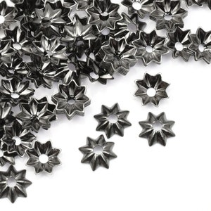 May include: A pile of black metal star-shaped bead caps. The caps have a raised center and a smooth, shiny finish.