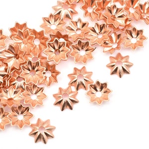 May include: A scattering of rose gold star-shaped metal beads. The beads have a raised, textured surface and a small hole in the center.