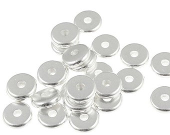 May include: A pile of silver-toned metal spacer beads. The beads are round with a hole in the center.