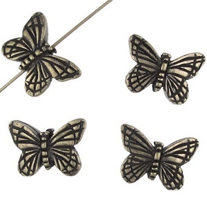 May include: Four antique silver butterfly beads. The beads are detailed with a textured design and are perfect for jewelry making.