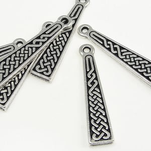 May include: Six silver-toned metal pendants with a black Celtic knot design. The pendants are shaped like long, narrow triangles.