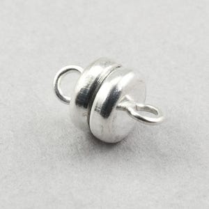 May include: Silver magnetic clasp for jewelry making. The clasp is round and has a smooth, polished finish.