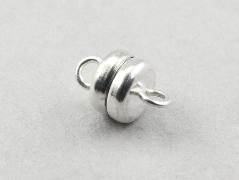 May include: Silver magnetic clasp for jewelry making. The clasp is round and has a smooth, polished finish.