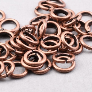 May include: A pile of copper jump rings, a type of jewelry finding, with a textured finish.