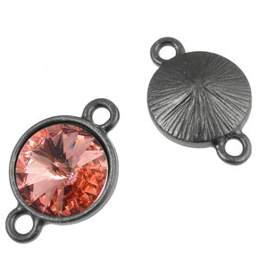 May include: Two silver-toned metal connector charms with a round shape. One charm features a clear pink crystal, the other has a textured surface.