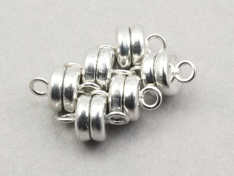 May include: Silver magnetic clasp for jewelry making. The clasp is made of multiple linked silver rings with a loop on each end.