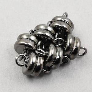 May include: A cluster of six silver magnetic clasps, connected by small loops, for jewelry making.