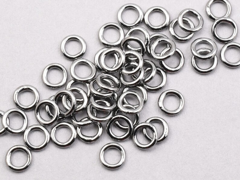 May include: A pile of silver jump rings, a type of metal ring used in jewellery making.