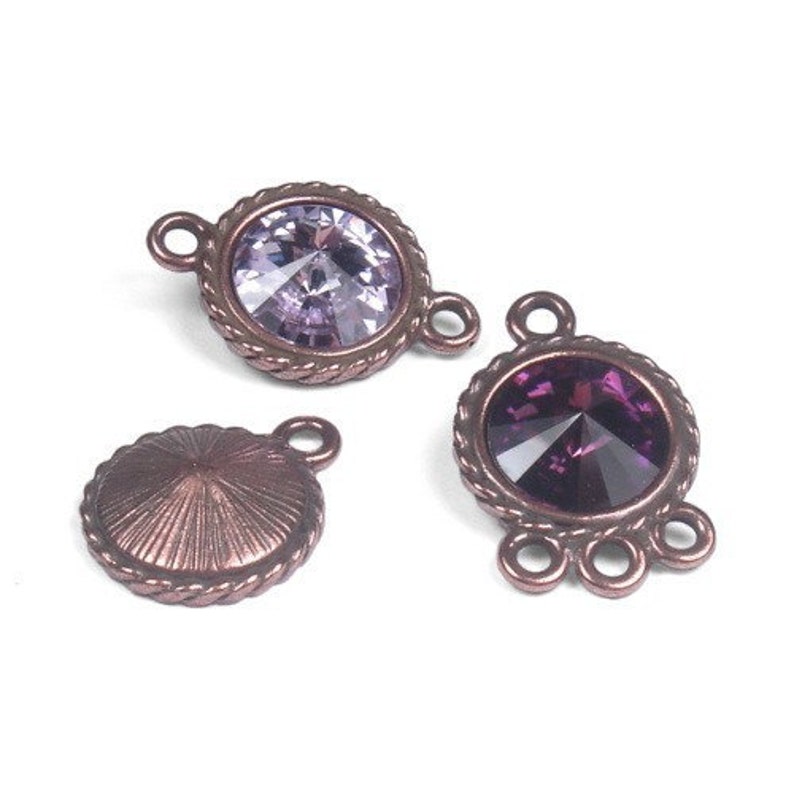 May include: Three antique copper-toned metal jewelry connectors with crystal accents. Two connectors feature a round crystal with a faceted design, one in a light purple and the other in a deep purple. The third connector is a round, flat disc with a textured surface.