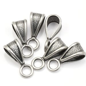 May include: Five silver-toned metal pendant bails with a textured finish. Each bail has a loop at the top and a small loop at the bottom.