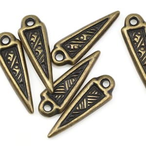 May include: Six antique gold-toned metal triangle charms with black etched designs. Each charm has a small loop at the top for attaching to jewelry or crafts.